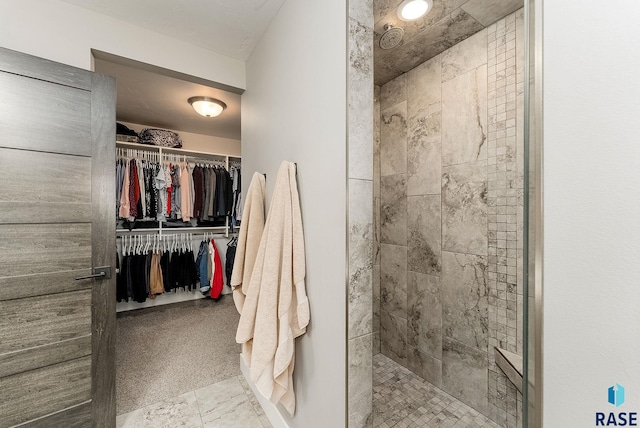 full bath with a walk in closet and tiled shower