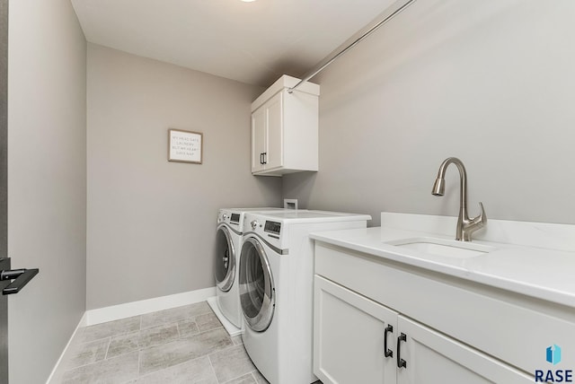 laundry area featuring washing machine and clothes dryer, a sink, cabinet space, and baseboards