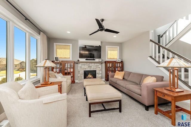 living area featuring stairs, plenty of natural light, a fireplace, and light carpet