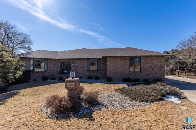 ranch-style house featuring brick siding and roof with shingles