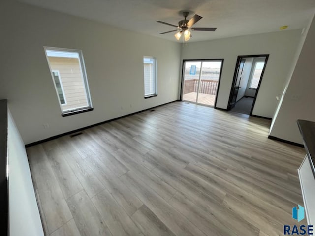 unfurnished living room with a ceiling fan, baseboards, visible vents, and light wood finished floors