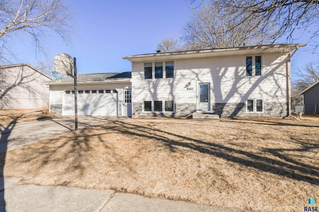 back of house with driveway, a garage, and a chimney