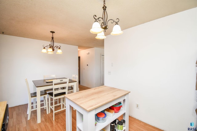 dining room featuring light wood-style floors, a chandelier, and a textured ceiling