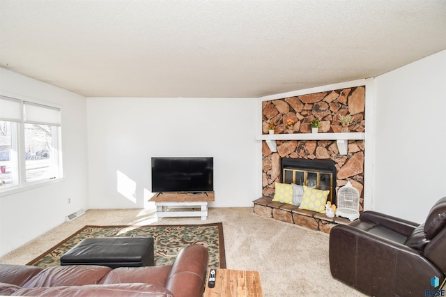 living room featuring carpet floors, visible vents, a textured ceiling, and a stone fireplace