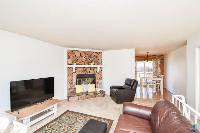 carpeted living room featuring a notable chandelier, a stone fireplace, and a textured ceiling