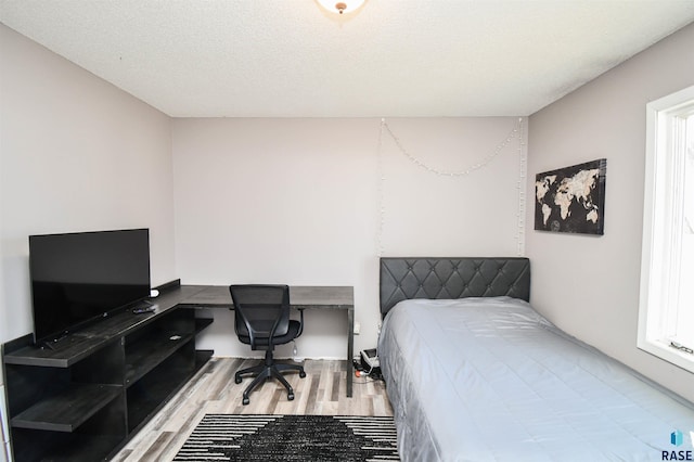 bedroom with a textured ceiling, multiple windows, and wood finished floors