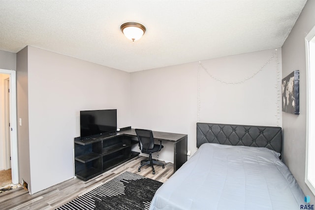 bedroom with a textured ceiling and light wood finished floors