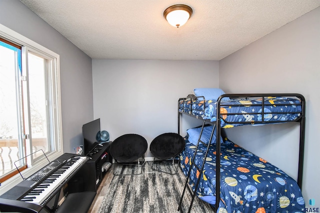 bedroom with multiple windows, a textured ceiling, and wood finished floors