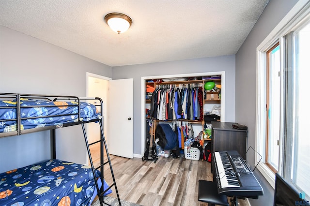 bedroom featuring a textured ceiling, a closet, multiple windows, and wood finished floors