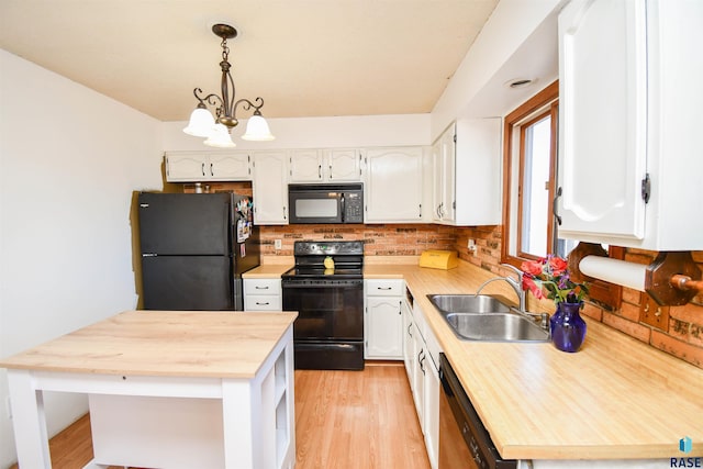 kitchen with backsplash, white cabinets, a sink, butcher block countertops, and black appliances