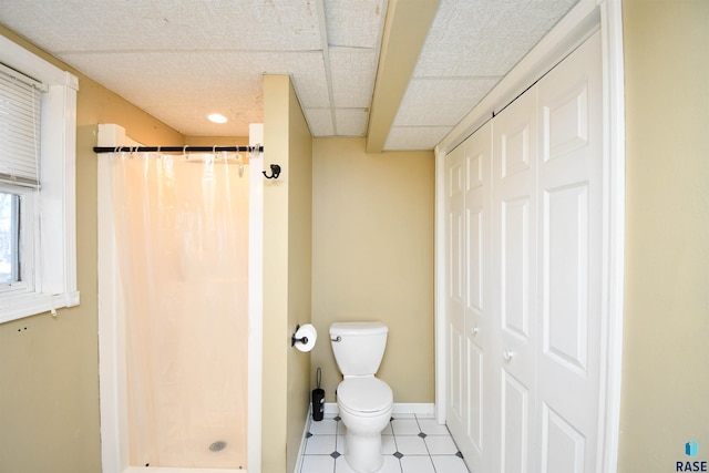 bathroom featuring a closet, a shower stall, toilet, and baseboards