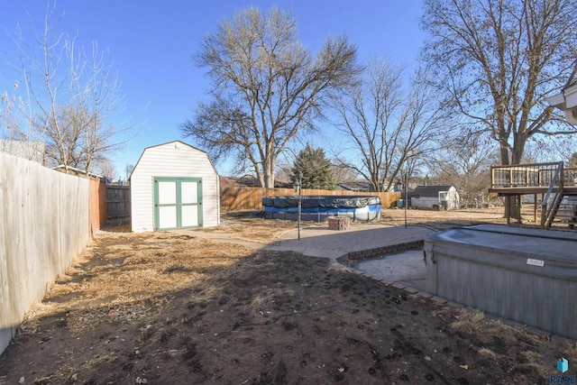 view of yard featuring a deck, a patio, a fenced backyard, an outdoor structure, and a storage unit