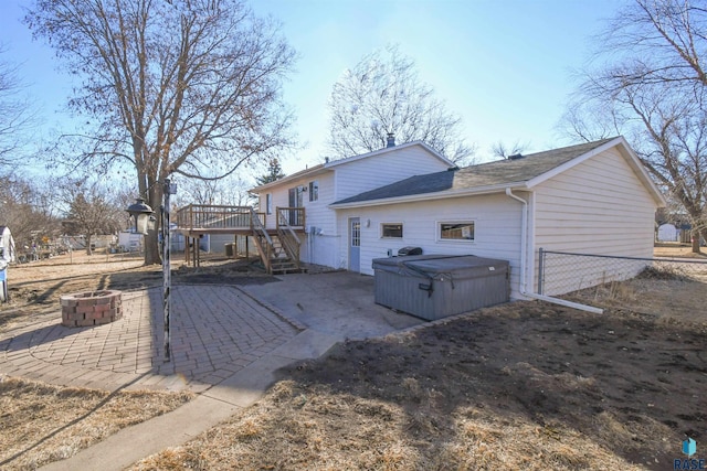 rear view of property with a patio, a hot tub, an outdoor fire pit, fence, and a deck