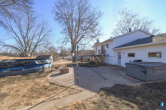 view of yard featuring an outdoor fire pit, a hot tub, a patio, stairs, and a wooden deck