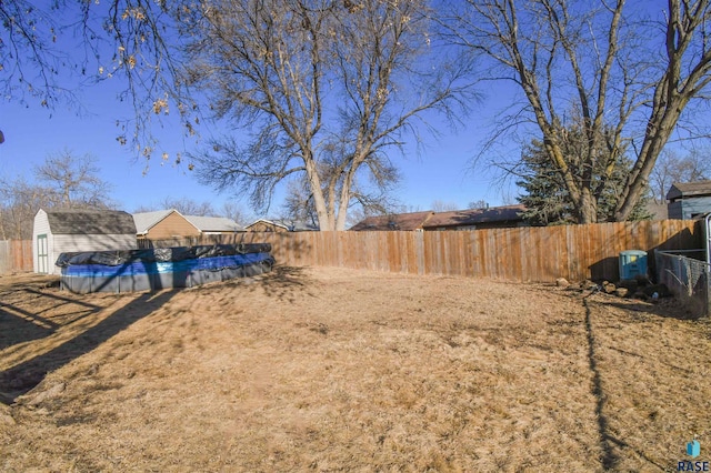 view of yard featuring a fenced backyard, a shed, a fenced in pool, and an outbuilding