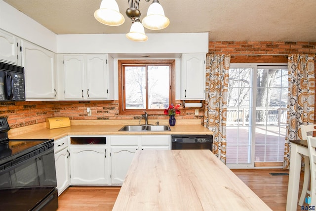 kitchen featuring black appliances, light wood-type flooring, a sink, and white cabinetry