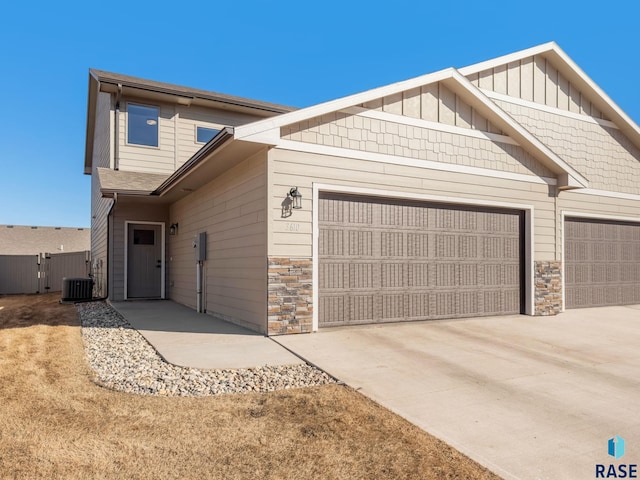 view of front facade with board and batten siding, stone siding, driveway, and an attached garage