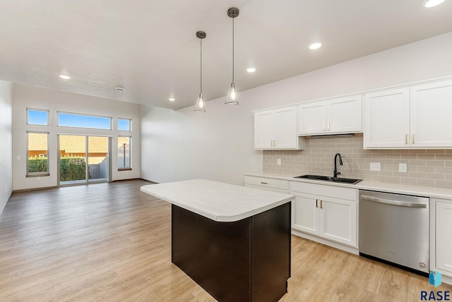 kitchen featuring light wood finished floors, dishwasher, backsplash, light countertops, and a sink