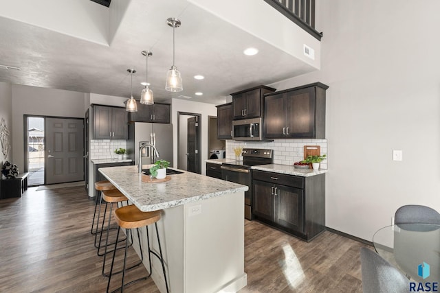 kitchen featuring dark brown cabinetry, visible vents, dark wood finished floors, stainless steel appliances, and a sink