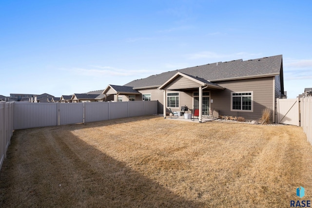 rear view of property with a patio, a lawn, a fenced backyard, and a gate