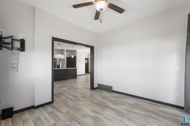 spare room with ceiling fan, light wood-style flooring, and baseboards