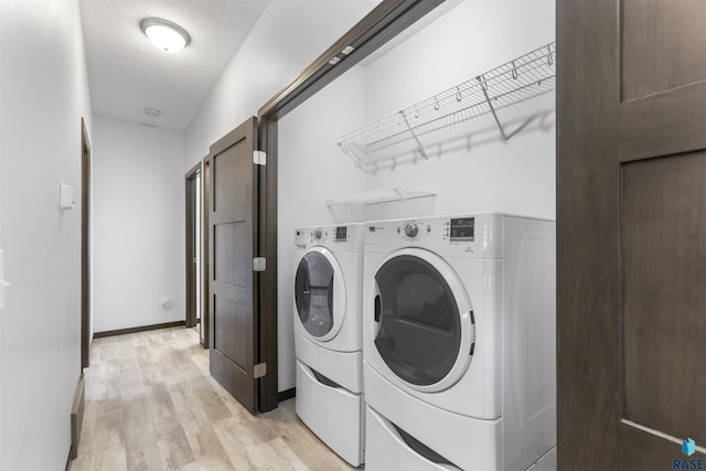 laundry room with laundry area, washing machine and dryer, light wood-style flooring, and baseboards