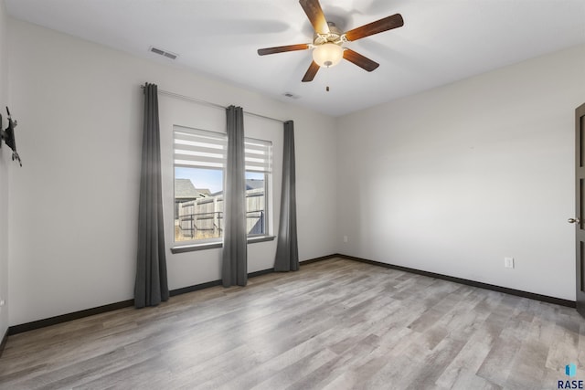 spare room featuring visible vents, ceiling fan, baseboards, and wood finished floors