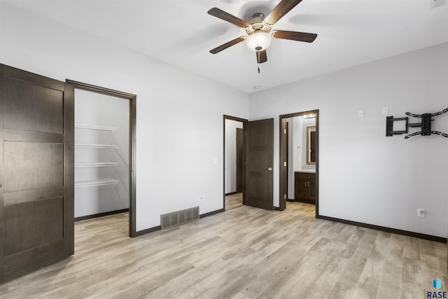 unfurnished bedroom with baseboards, a spacious closet, visible vents, and light wood-style floors