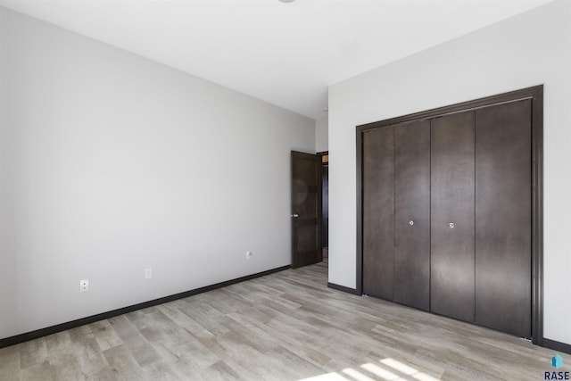 unfurnished bedroom with light wood-style floors, a closet, and baseboards