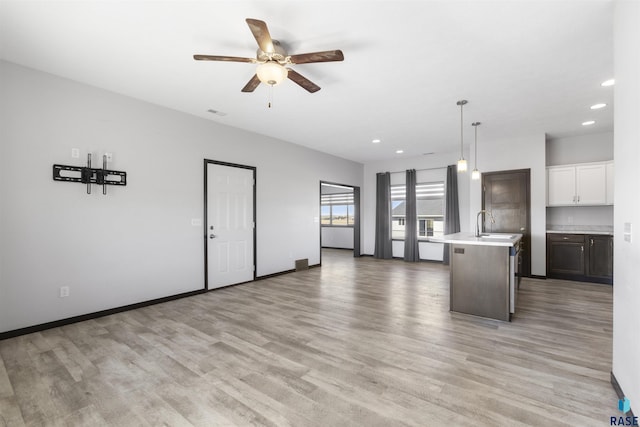 kitchen with light wood finished floors, baseboards, light countertops, and open floor plan