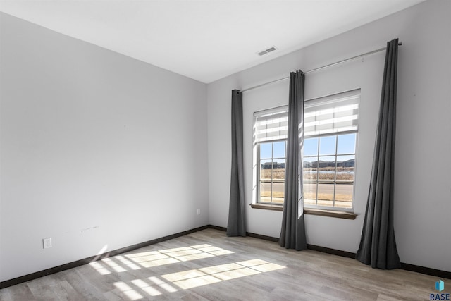 unfurnished room with visible vents, light wood-style flooring, and baseboards