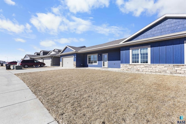 ranch-style home featuring an attached garage, stone siding, driveway, and board and batten siding