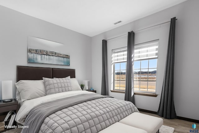 bedroom with baseboards, visible vents, and wood finished floors