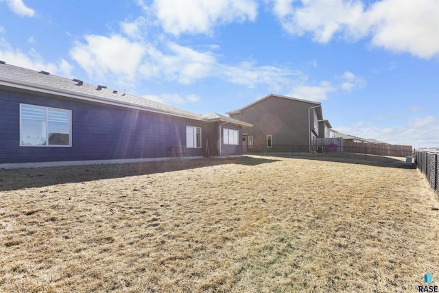 back of property with fence and a lawn