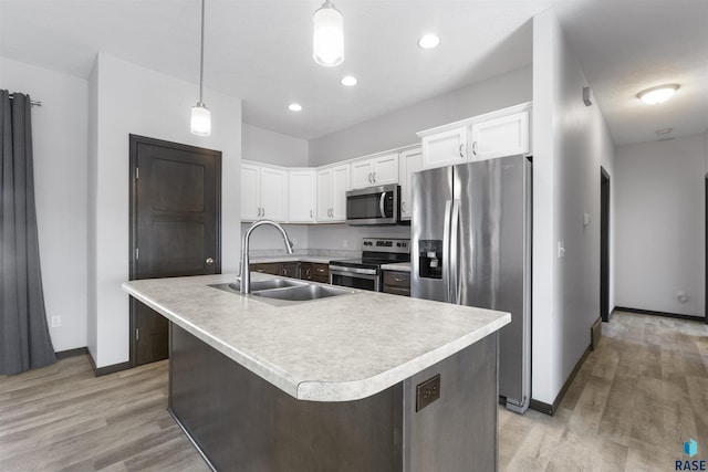 kitchen with light countertops, light wood-style flooring, appliances with stainless steel finishes, white cabinetry, and a sink