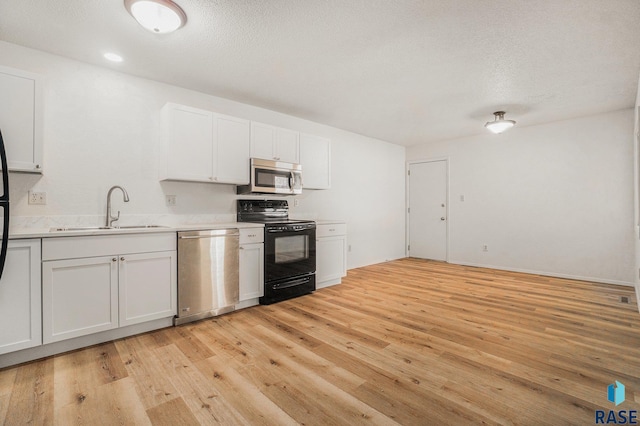 kitchen with stainless steel appliances, light countertops, a sink, and light wood finished floors