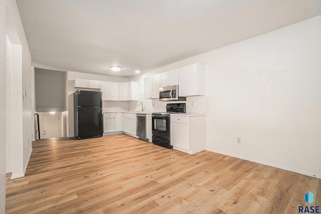 kitchen featuring light countertops, light wood-type flooring, white cabinetry, and black appliances