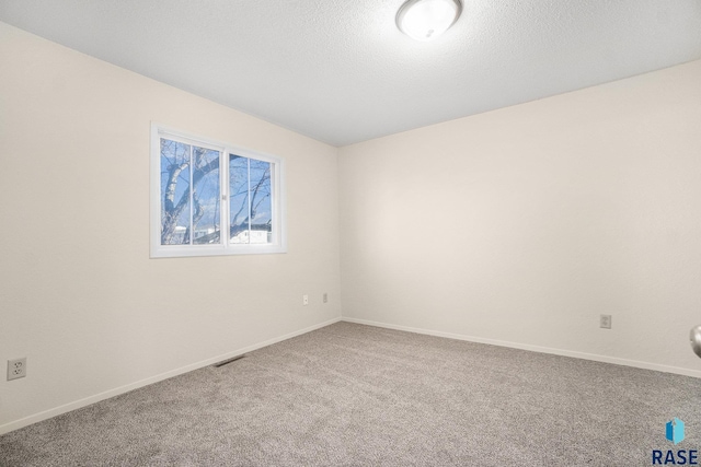 empty room with a textured ceiling, carpet floors, visible vents, and baseboards