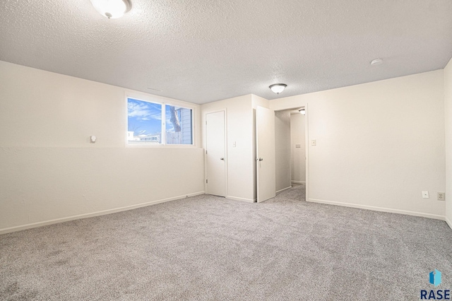 unfurnished bedroom with carpet, a textured ceiling, and baseboards