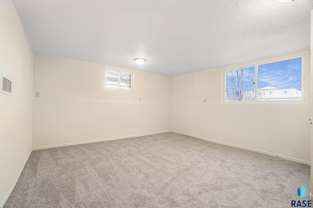 basement with carpet floors, visible vents, baseboards, and a textured ceiling