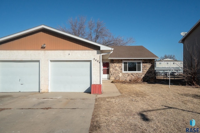 single story home with a shingled roof, stone siding, driveway, and an attached garage