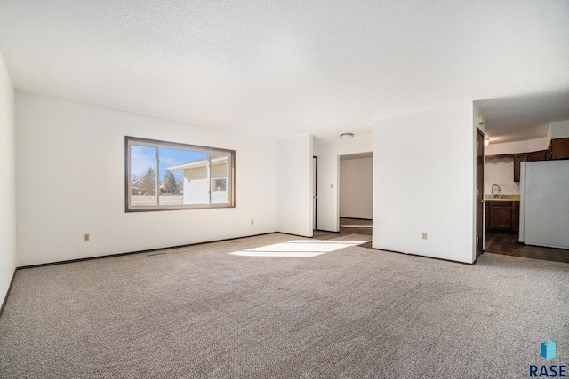 interior space featuring carpet floors, a textured ceiling, baseboards, and a sink