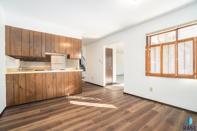 kitchen featuring baseboards, visible vents, dark wood-type flooring, a peninsula, and light countertops