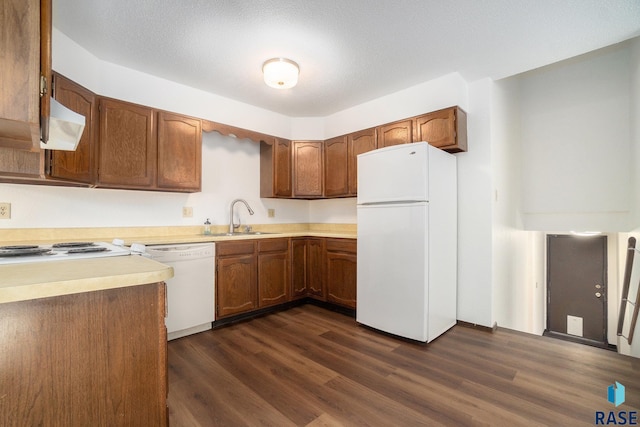 kitchen featuring light countertops, white appliances, dark wood-style flooring, and a sink