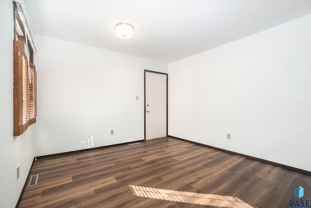 unfurnished room with baseboards, visible vents, and wood finished floors