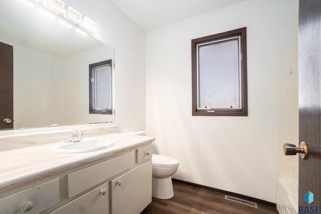 full bath with visible vents, toilet, a bathing tub, vanity, and wood finished floors