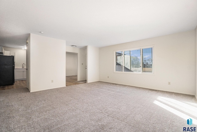 carpeted empty room featuring visible vents and a sink