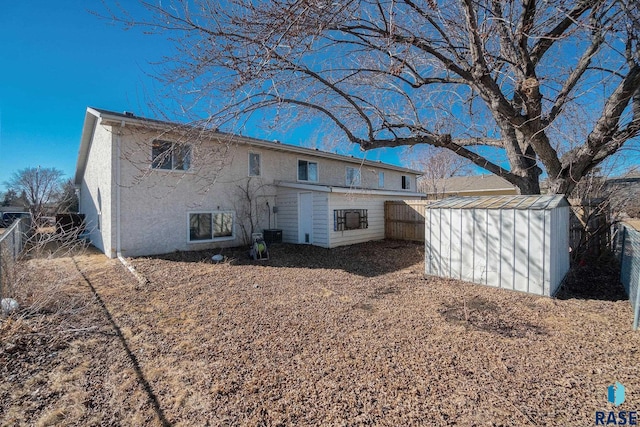 back of house with a fenced backyard, an outdoor structure, and a storage unit