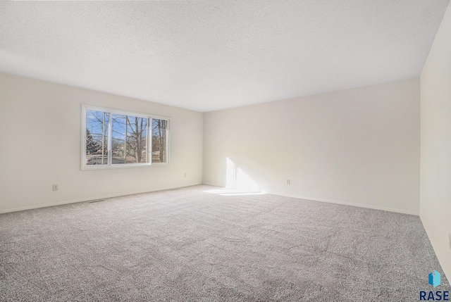 empty room featuring carpet floors, visible vents, and a textured ceiling