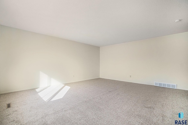 unfurnished room with a textured ceiling, visible vents, and carpet flooring